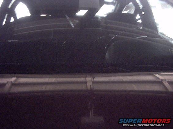 Dark car interior with dashboard and windshield visible, showing wiper blades and reflections